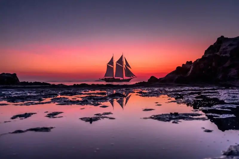 A phinisi under sail at sunset
