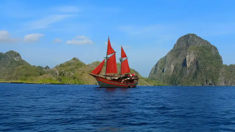 A red-sailed phinisi under way